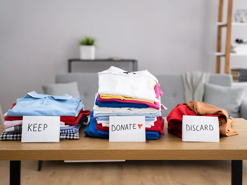 clothes organized behind signs of keep donate or discard