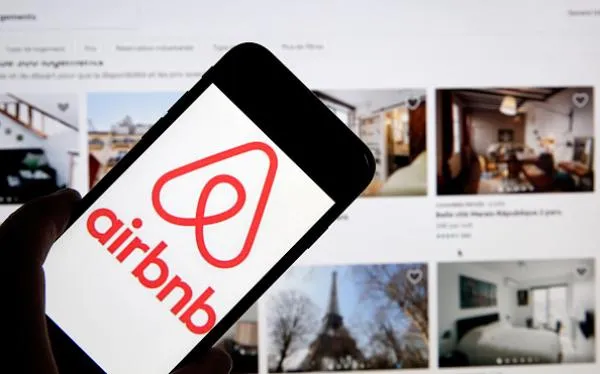 airbnb logo in a phone screen in front of a youtube page
