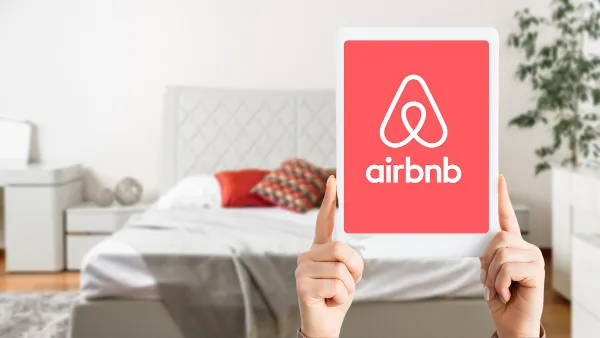 Airbnb on the screen of a tablet in front of a clean bed