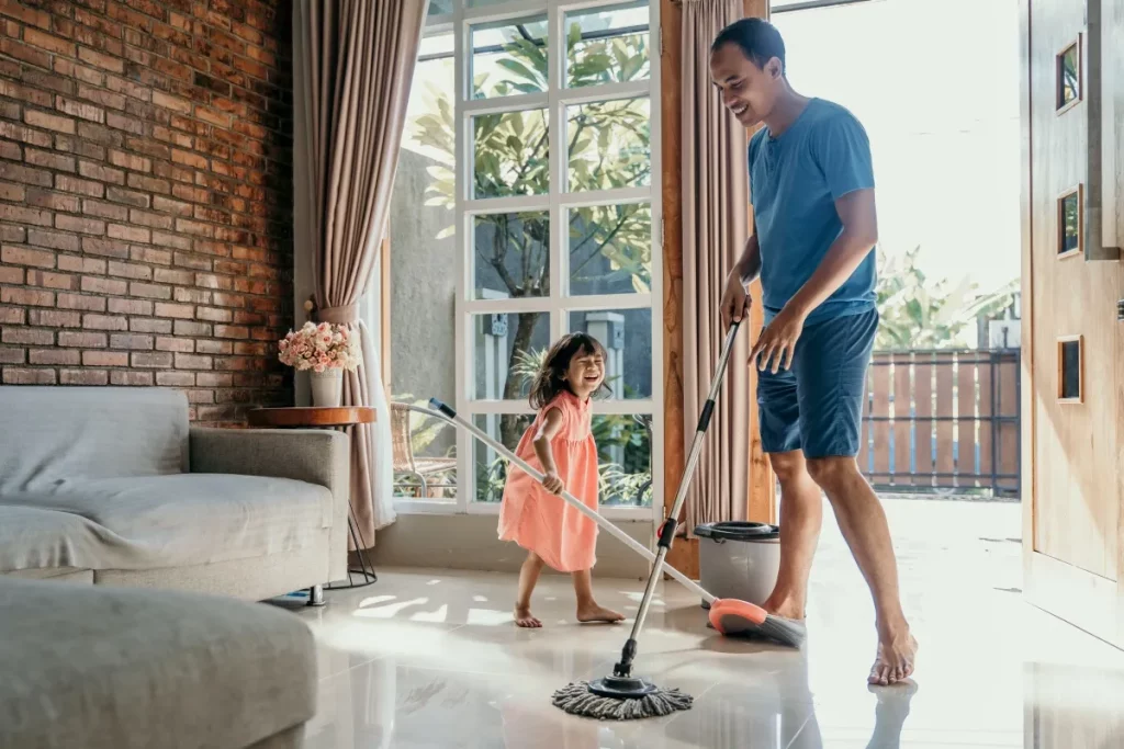dad developing cleaning habits in kids by cleaning a room with his daughter